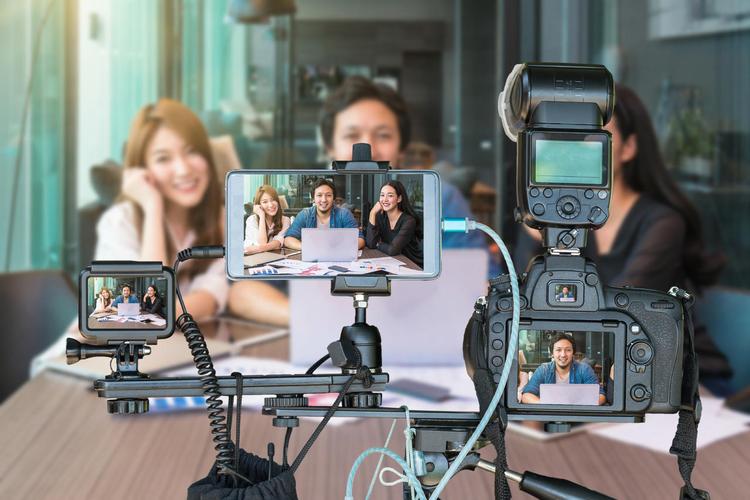 亚洲商界人士通过专业的相机与智能手机和动作摄像头的三脚架现场直播